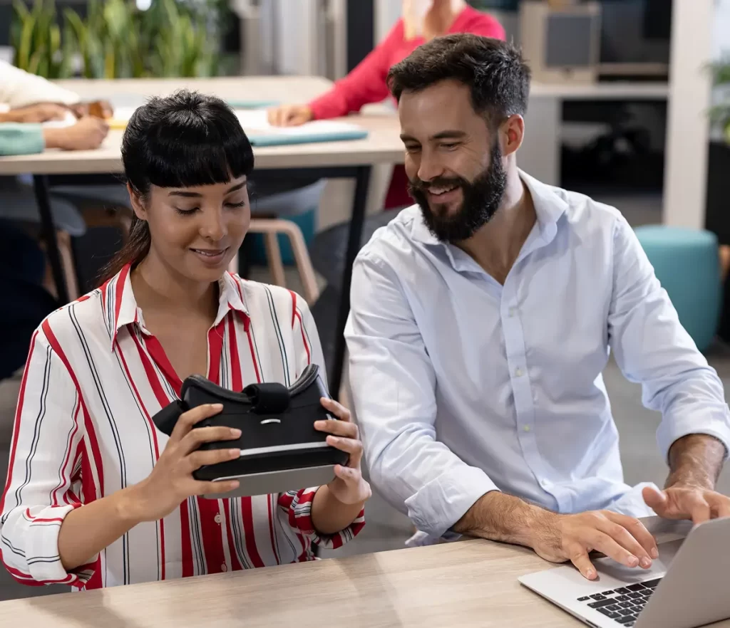 A woman explores virtual reality through a headset while a man assists her with the testing process.